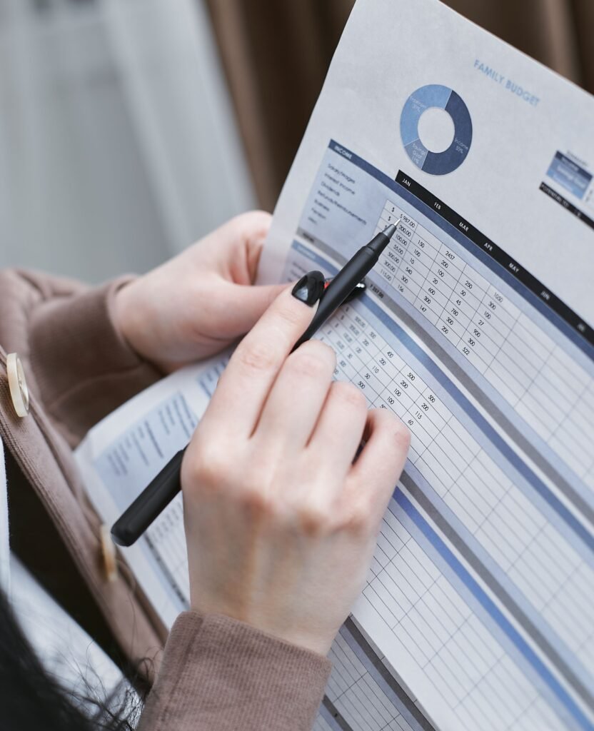How Much Should Your Emergency Fund Be in 2026? The Real Number Based on Your Life Hands holding a pen review a family budget document with graphs and tables.
